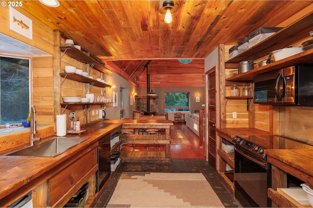 kitchen featuring butcher block counters, sink, stainless steel electric range, and a wood stove