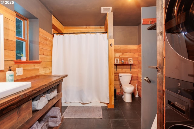 bathroom featuring toilet, sink, wooden walls, and tile patterned flooring