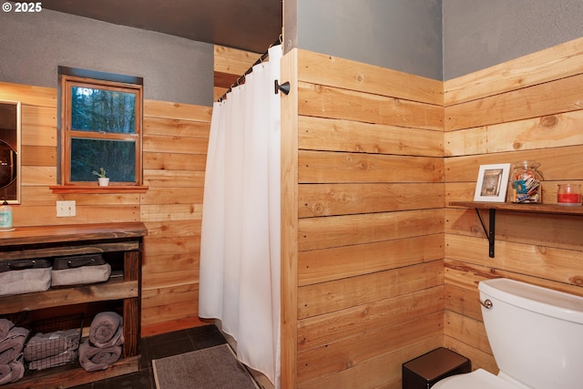 bathroom featuring toilet and wood walls