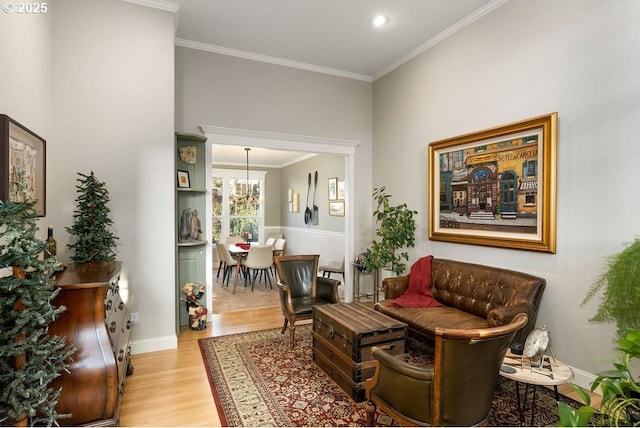 living area with baseboards, crown molding, and light wood finished floors