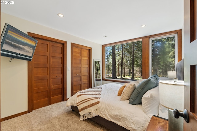 carpeted bedroom featuring multiple closets and recessed lighting