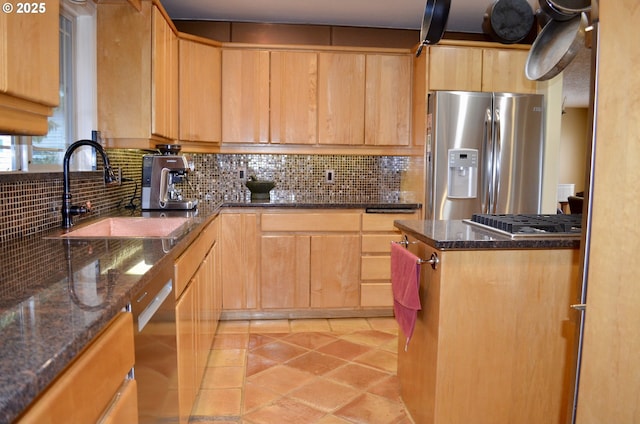 kitchen featuring decorative backsplash, light brown cabinetry, appliances with stainless steel finishes, and a sink