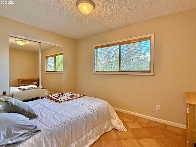 tiled bedroom featuring baseboards, a closet, and a textured ceiling