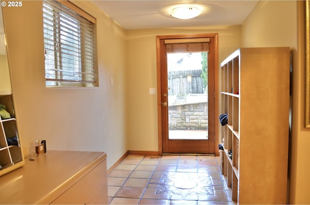 doorway to outside with baseboards and light tile patterned flooring