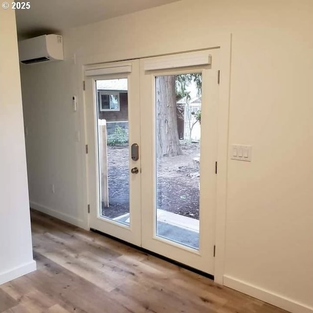 entryway with french doors, baseboards, an AC wall unit, and wood finished floors