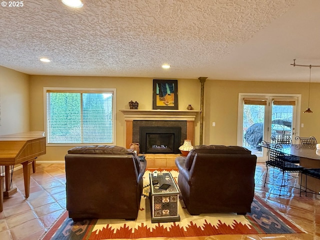 living area with recessed lighting, plenty of natural light, a fireplace with raised hearth, and a textured ceiling