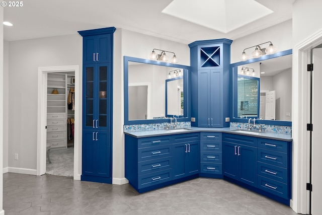 bathroom with double vanity, a sink, a walk in closet, and recessed lighting