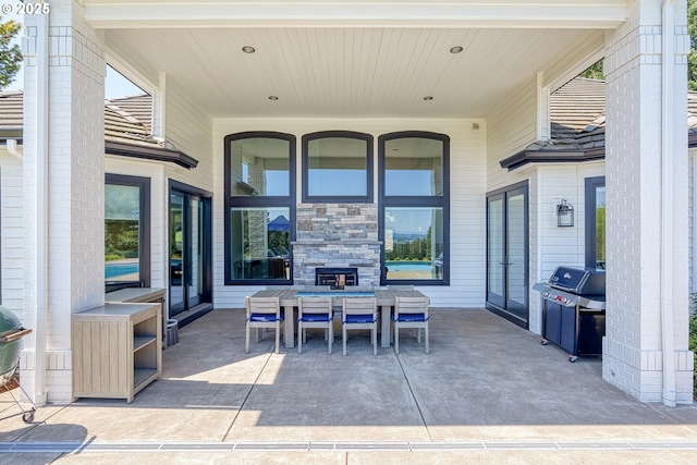 view of patio / terrace featuring outdoor dining space, grilling area, and an outdoor stone fireplace