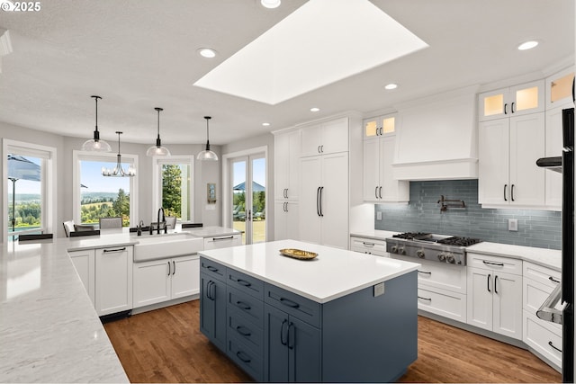 kitchen featuring stainless steel gas cooktop, white cabinets, decorative backsplash, and a sink