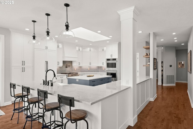 kitchen with wall chimney range hood, a center island, tasteful backsplash, a sink, and stainless steel appliances