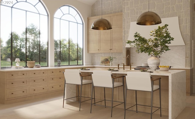 kitchen with backsplash, a center island with sink, a breakfast bar area, and cream cabinetry