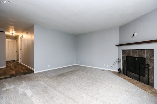 unfurnished living room with a tiled fireplace and dark colored carpet