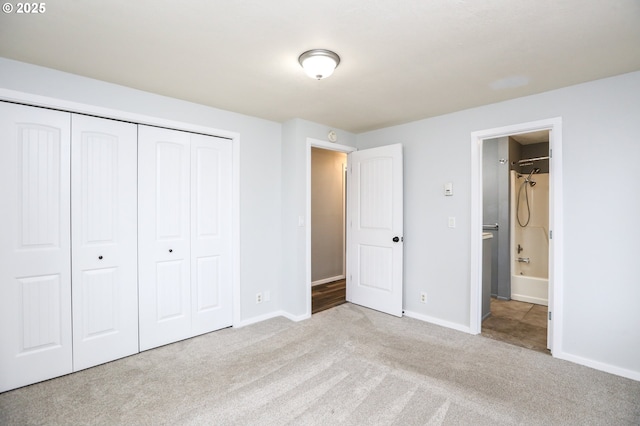 unfurnished bedroom featuring ensuite bath, a closet, and light colored carpet