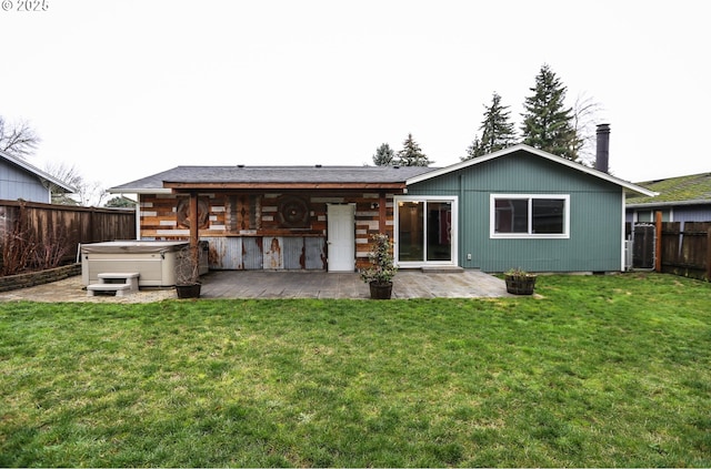 rear view of property with a yard, a hot tub, and a patio area