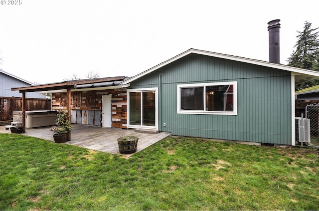 back of property with a yard, a patio, and a hot tub