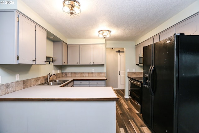 kitchen featuring sink, gray cabinets, dark hardwood / wood-style flooring, kitchen peninsula, and stainless steel appliances