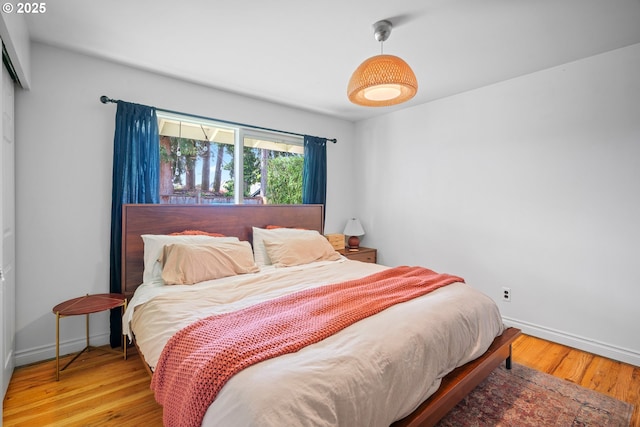bedroom with baseboards, wood finished floors, and a closet