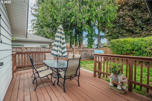 wooden terrace with a fenced backyard and outdoor dining space