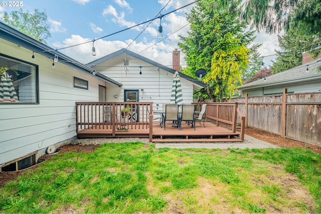 back of property featuring fence, a wooden deck, outdoor dining area, and a yard
