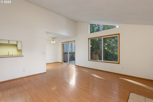 unfurnished living room featuring lofted ceiling, ceiling fan, and light wood-type flooring