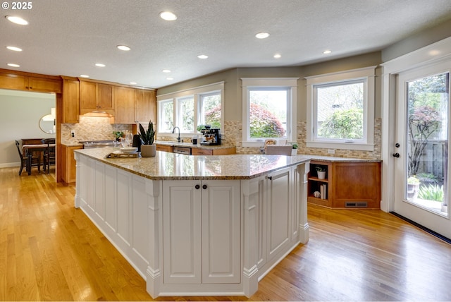 kitchen featuring a kitchen island, recessed lighting, a textured ceiling, tasteful backsplash, and light wood finished floors