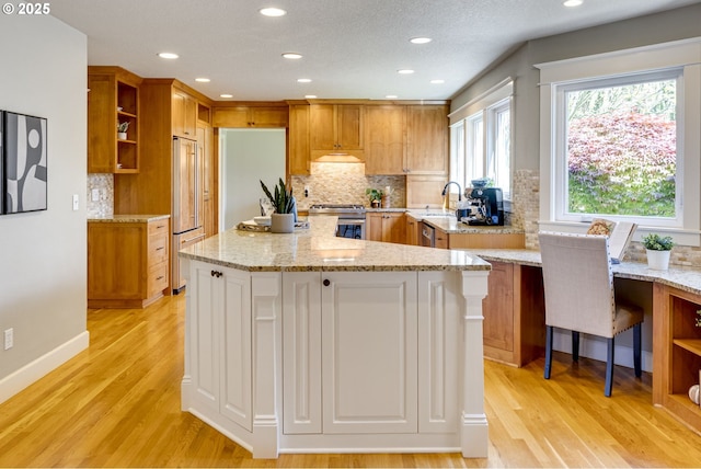 kitchen featuring open shelves, light wood finished floors, a center island, backsplash, and premium appliances