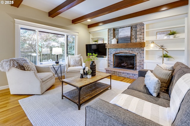 living area featuring baseboards, a fireplace, wood finished floors, and beam ceiling