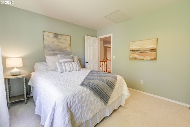 bedroom with light colored carpet, attic access, and baseboards