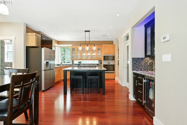 20817 NE 101st Ct, Battle Ground, WA 98604 - kitchen featuring stainless steel appliances, backsplash, glass insert cabinets, light brown cabinets, and a center island