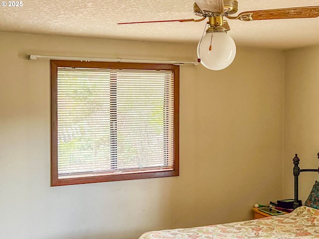 unfurnished bedroom featuring multiple windows, a textured ceiling, and ceiling fan