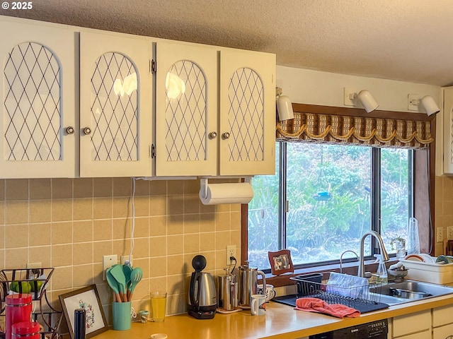 kitchen with tasteful backsplash, black dishwasher, sink, and a textured ceiling