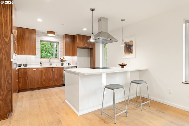 3105 NW Blue Sky Ln, Portland, OR 97229 - kitchen featuring brown cabinetry, light wood-type flooring, exhaust hood, and backsplash