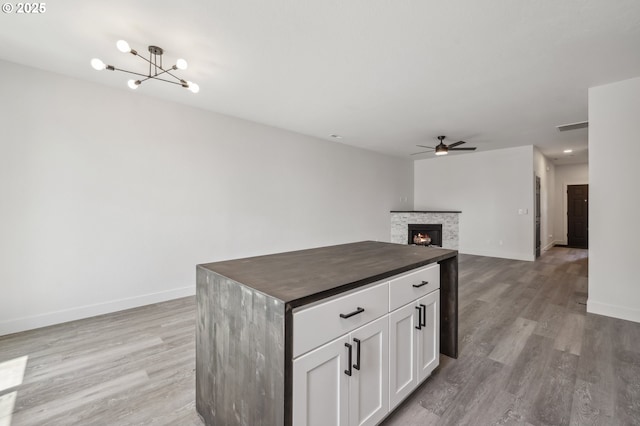 5958 SE 16th Loop, Gresham, OR 97080 - kitchen with a ceiling fan, light wood-style flooring, baseboards, and a stone fireplace