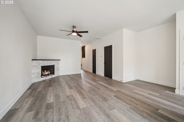 5958 SE 16th Loop, Gresham, OR 97080 - unfurnished living room with wood finished floors, a ceiling fan, a stone fireplace, and baseboards