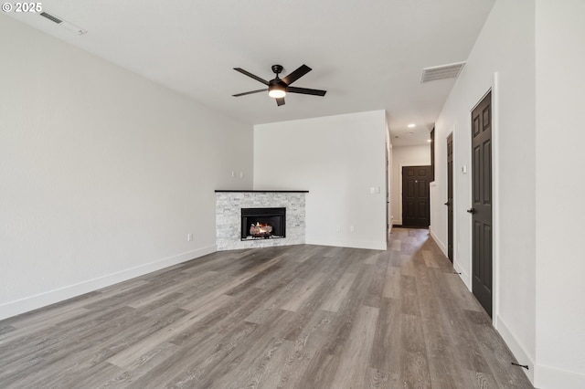 5958 SE 16th Loop, Gresham, OR 97080 - unfurnished living room with wood finished floors, ceiling fan, a stone fireplace, and baseboards
