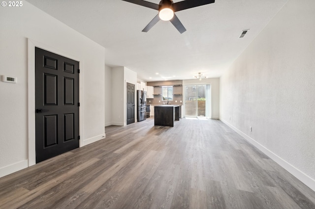 5958 SE 16th Loop, Gresham, OR 97080 - unfurnished living room featuring wood finished floors, ceiling fan, baseboards, and a sink
