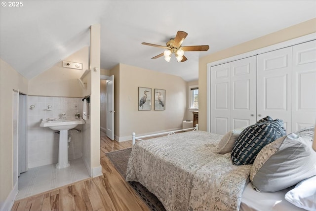 bedroom with a closet, baseboards, a ceiling fan, light wood finished floors, and ensuite bath