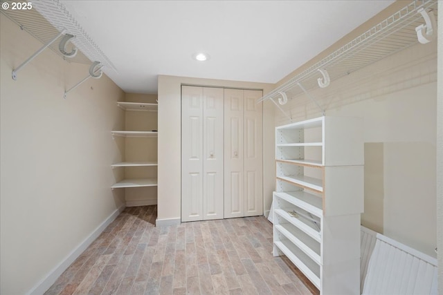 walk in closet with light wood finished floors