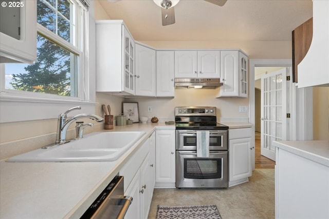 kitchen with a sink, light countertops, stainless steel appliances, and under cabinet range hood
