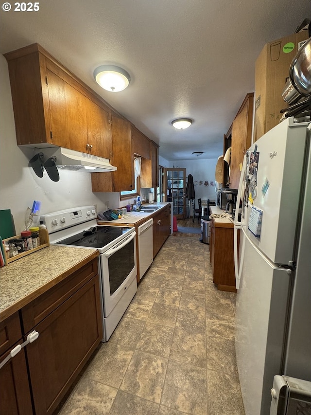 318 W 20th St, The Dalles, OR 97058 - kitchen with white appliances, under cabinet range hood, light countertops, a sink, and brown cabinets