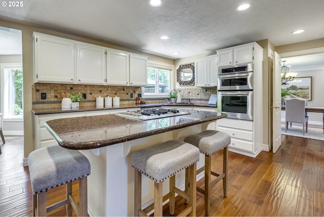 17865 NW Elk Meadow Ln, Portland, OR 97229 - kitchen with stainless steel appliances, dark wood finished floors, white cabinets, baseboards, and recessed lighting