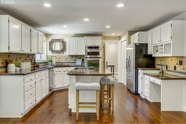 17865 NW Elk Meadow Ln, Portland, OR 97229 - kitchen with a sink, stainless steel appliances, a center island, white cabinetry, and decorative backsplash