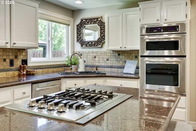 17865 NW Elk Meadow Ln, Portland, OR 97229 - kitchen featuring appliances with stainless steel finishes, a sink, white cabinets, and backsplash