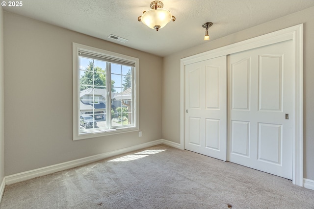 17865 NW Elk Meadow Ln, Portland, OR 97229 - unfurnished bedroom featuring carpet, a closet, baseboards, and a textured ceiling
