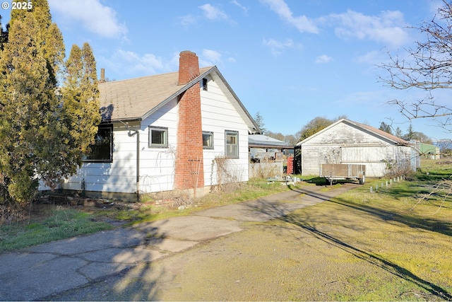 view of property exterior featuring a shingled roof and a chimney