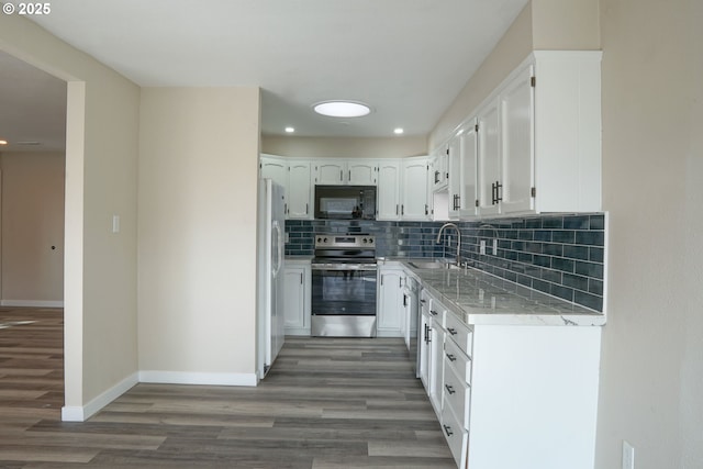 kitchen with a sink, stainless steel appliances, white cabinets, light wood-style floors, and tasteful backsplash