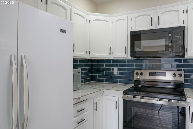 kitchen with backsplash, black microwave, electric stove, freestanding refrigerator, and white cabinetry