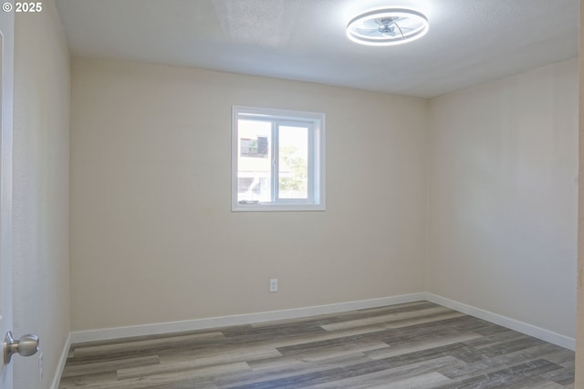 unfurnished room with baseboards and wood finished floors