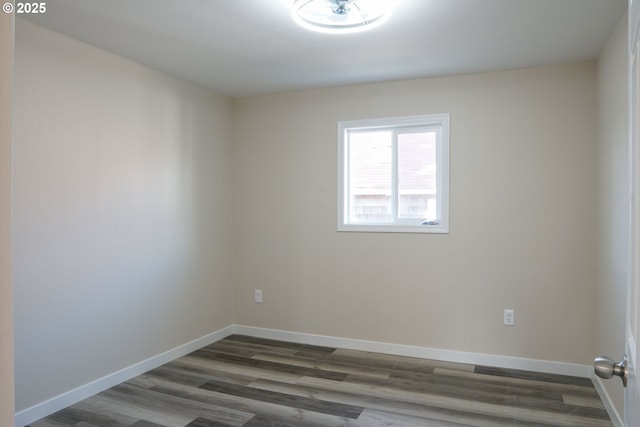 empty room featuring dark wood-type flooring and baseboards