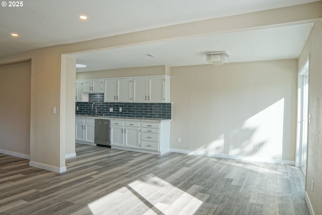 kitchen featuring tasteful backsplash, stainless steel dishwasher, wood finished floors, white cabinets, and light countertops